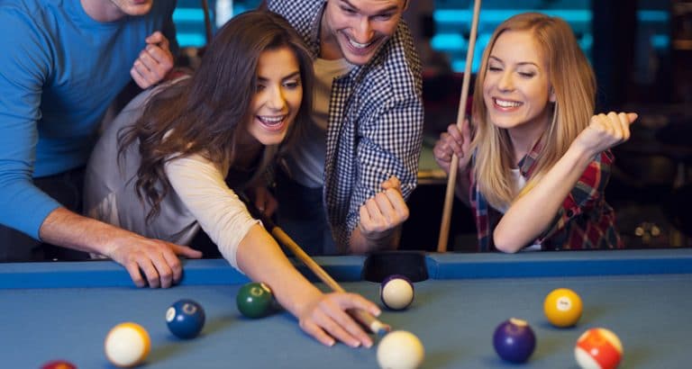 Friends cheering while their friend aiming for billiards ball