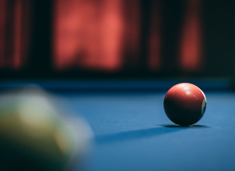 Blue pool table felt with a red ball rolling towards it.