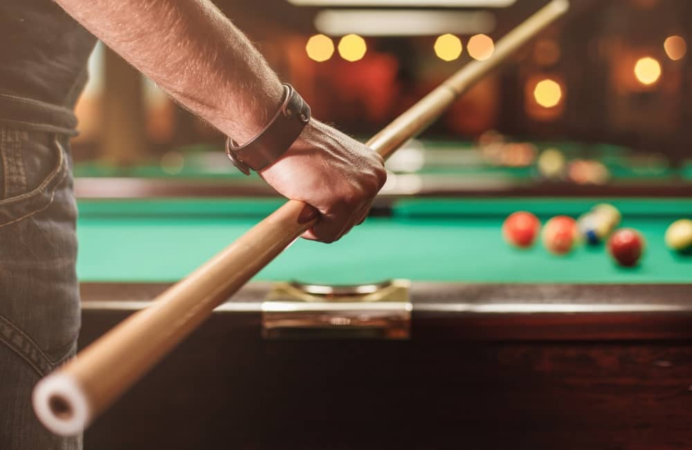 Man playing billiards holding cue.
